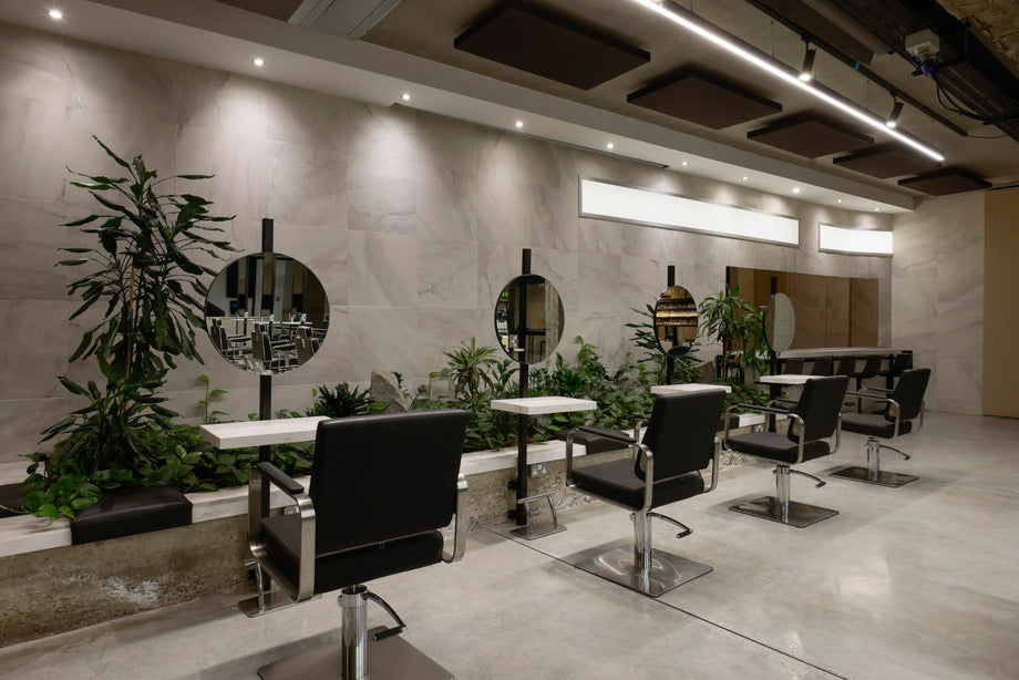 Modern salon interior with black chairs, mirrors, and plants.