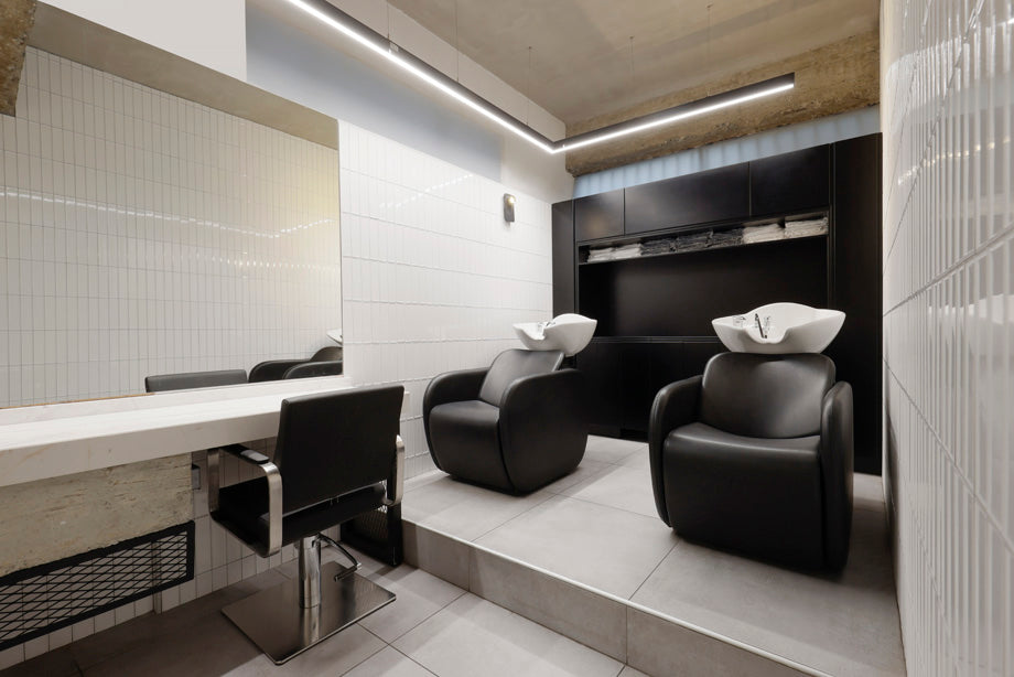 Salon interior with black hair washing chairs and a mirror.
