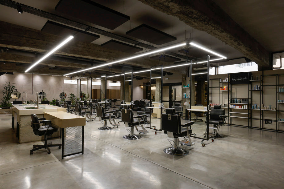 Modern salon space with stations, mirrors, and product shelves.